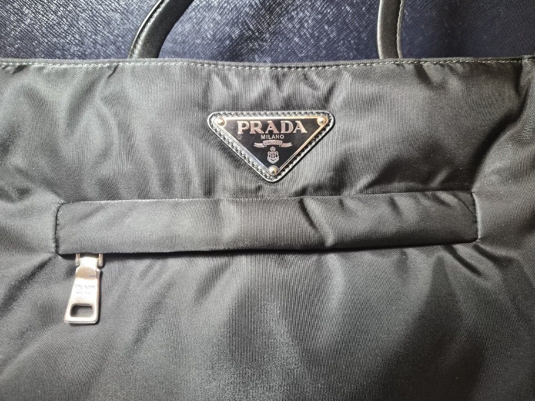 Prada Black Nylon Tote Bag (Category: Luxury Bags & Wallets) located in Manila. Submitted by prelovedbyc.hannah (Listing ID 1471232390, Image 2). Description: - Authentic Prada black nylon tote with authenticity certificate card - Premium leather handles and iconic triangle logo plaque - Exterior and interior zipper compartments with signature jacquard lining - Interior Prada Made in Italy plaque - Includes original box, dust bag, and authenticit