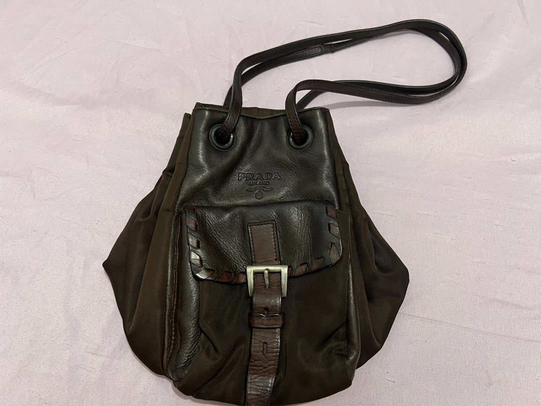 Prada Brown Nylon Leather Shoulder Bag (Category: Luxury Bags & Wallets) located in Manila. Submitted by czaaay (Listing ID 1471125644, Image 1). Description: - Authentic Prada shoulder bag in rich dark brown - Premium combination of durable nylon and leather trims - Secure top drawstring closure with dual shoulder straps - Convenient front flap pocket featuring a stylish buckle strap - Iconic debossed Prada Milano logo detail - Spacious and vers