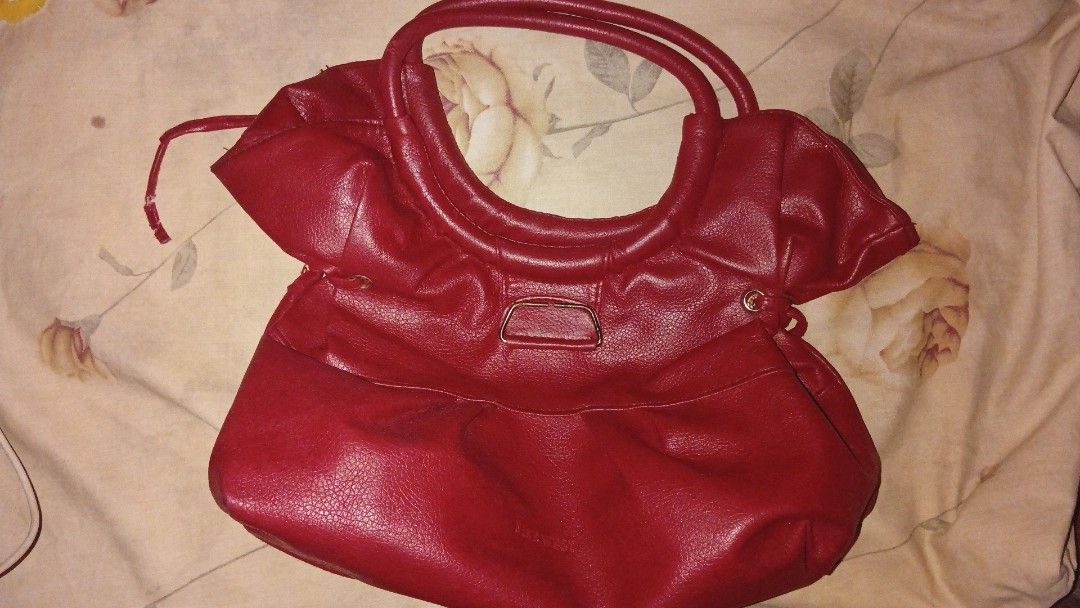 Red Leather Shoulder Bag with Gold Hardware (Category: Luxury Bags & Wallets) located in Iligan City. Submitted by freiko (Listing ID 1471275538, Image 1). Description: - Color: Bright red - Material: Soft faux leather with gold-tone hardware - Straps: Double top handles - Details: Chic side drawstring accents - Interior: Spacious beige patterned fabric lining - Closure: Secure top zipper closure - Condition: Brand new/Excellent.