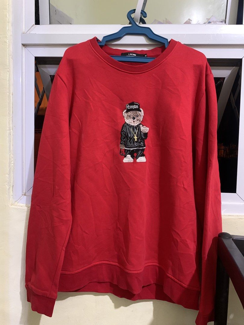 Red Sweatshirt with Bear Graphic (Category: Coats, Jackets and Outerwear) located in Manila. Submitted by chelle_thrifted_shack (Listing ID 1471236877, Image 1). Description: Bright red LAKING crewneck sweatshirt in size M. Features a cool embroidered teddy bear graphic with a black outfit, cap, and gold chain. Comfortable pullover style, perfect for casual wear..
