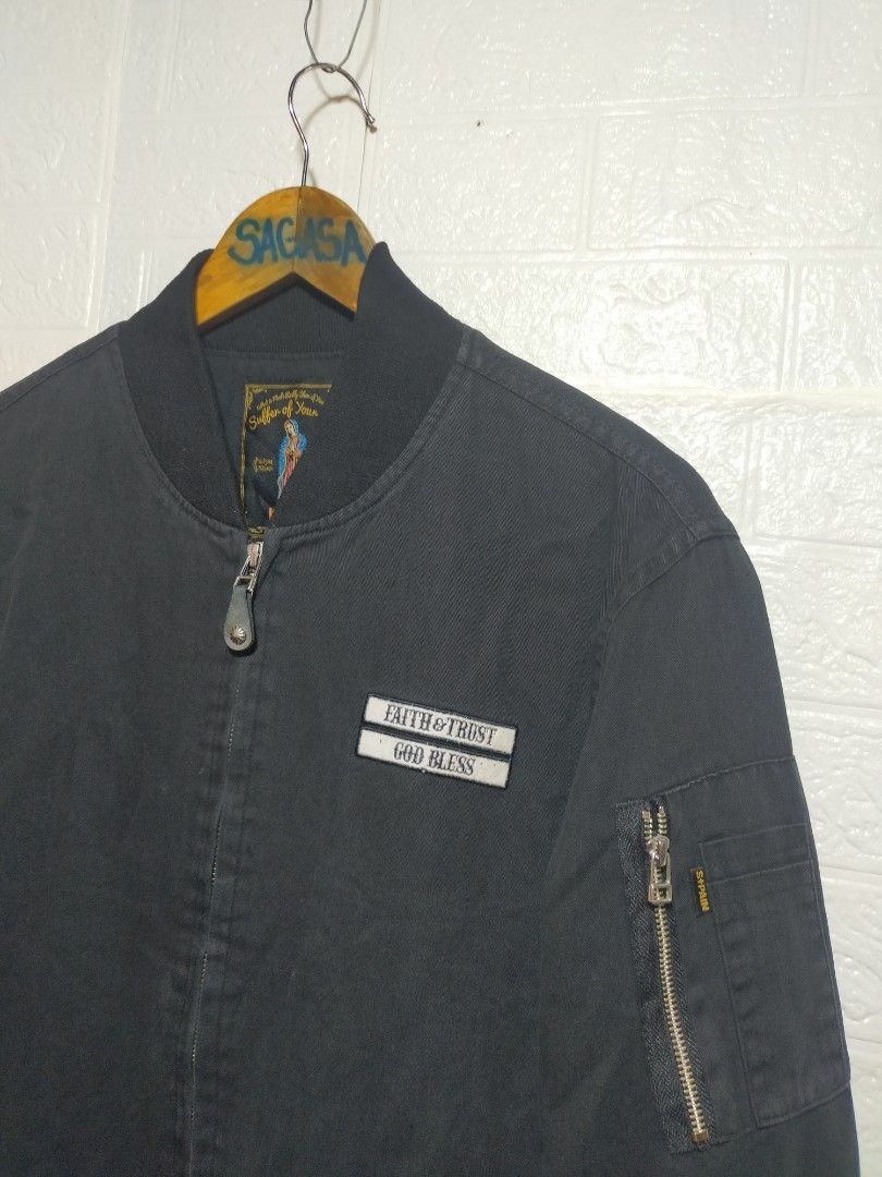 Saintpain Black Bomber Jacket with Patches (Category: Coats, Jackets and Outerwear) located in Valencia. Submitted by cabisaythriftshop (Listing ID 1471223551, Image 3). Description: - Brand: Saintpain - Color: Black - Material: Durable canvas - Closure: Full zip - Details: Ribbed collar, cuffs, and hem - Pockets: Utility pocket with zipper on the left sleeve - Patches: 'Faith & Trust God Bless' chest patch, Virgin Mary right sleeve graphic, and 