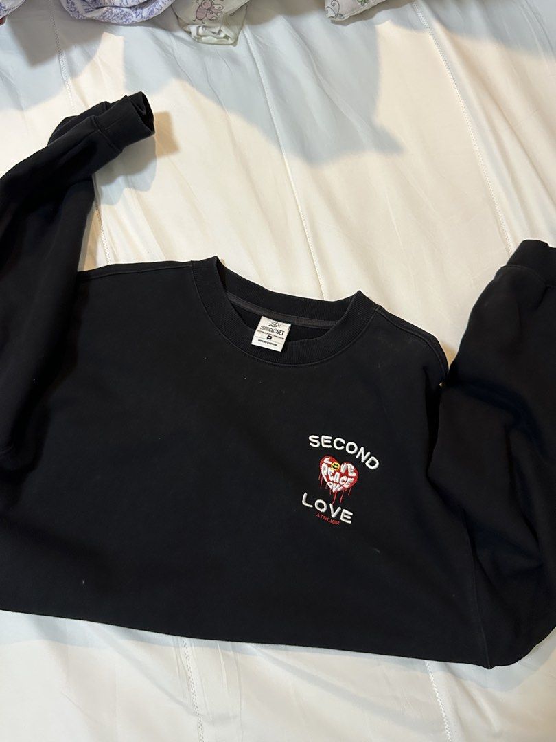Second Love Peace & Love Sweatshirt (Category: Longsleeves) located in Bulacan. Submitted by juyeonloey (Listing ID 1471262916, Image 3). Description: - Brand: 2nd Closet Atelier - Color: Black - Size: M (tag on collar) - Front details: Embroidered 'SECOND LOVE' text with red heart and smiley face - Back details: White cursive 'Peace & Love' lettering - Pit to pit: ~24.5 inches - Length: ~28.5 inches - Features ribbed cuffs and hem, clean piece w