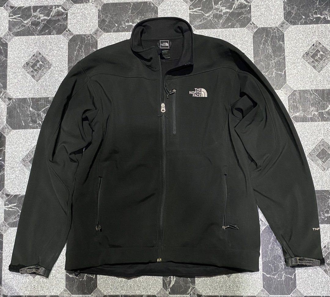 The North Face Black Jacket (Category: Coats, Jackets and Outerwear) located in Baguio. Submitted by flynes (Listing ID 1471264305, Image 1). Description: - Brand: The North Face - Style: Men's Softshell Jacket - Color: Black - Size: Men's Large Regular - Dimensions: L-27.5”, w-23.5”, sleeves-26” - Lining: Warm fleece interior - Features: Full zip closure, zippered chest pocket, two hand pockets, and adjustable velcro cuffs - Branding: Embroidere