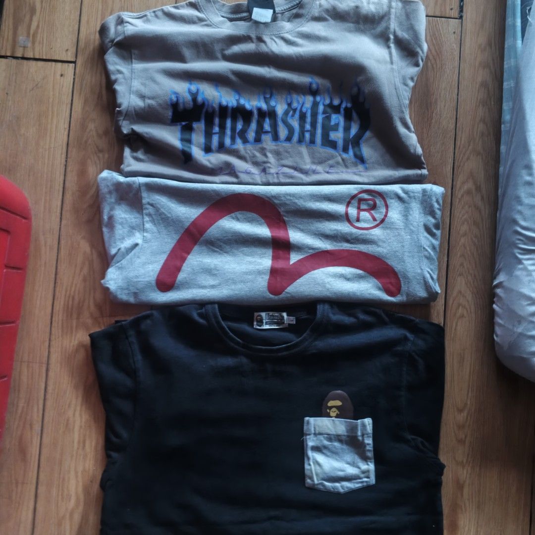 Thrasher Evisu Bape Graphic T-Shirt Bundle (Category: Tshirts & Polo Shirts ) located in Paranaque City. Submitted by thriftine5 (Listing ID 1471130824, Image 2). Description: - Bundle of 3 iconic graphic tees - 1st: Brown Thrasher flame logo tee - 2nd: Grey Evisu tee with large red seagull graphic and trademark R - 3rd: Black A Bathing Ape pocket tee featuring an ape peeking out - Sizes vary slightly across the bundle - Perfect streetwear staple