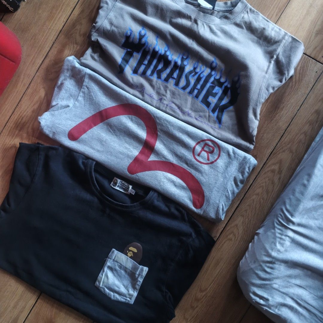 Thrasher Evisu Bape Graphic T-Shirt Bundle (Category: Tshirts & Polo Shirts ) located in Paranaque City. Submitted by thriftine5 (Listing ID 1471130824, Image 1). Description: - Bundle of 3 iconic graphic tees - 1st: Brown Thrasher flame logo tee - 2nd: Grey Evisu tee with large red seagull graphic and trademark R - 3rd: Black A Bathing Ape pocket tee featuring an ape peeking out - Sizes vary slightly across the bundle - Perfect streetwear staple