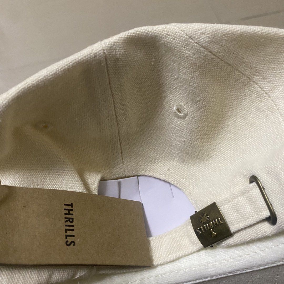 Thrills Off White Embroidered Logo Baseball Cap (Category: Caps & Hats) located in Quezon City. Submitted by capsanywhere (Listing ID 1471197136, Image 3). Description: - Brand: Thrills - Color: Off-white - Material: Canvas - Design: Embroidered branding on front panel - Closure: Adjustable strapback with bronze-tone metal buckle (features stamped palm tree logo) - Condition: Brand new with internal tags and original swing tag attached.