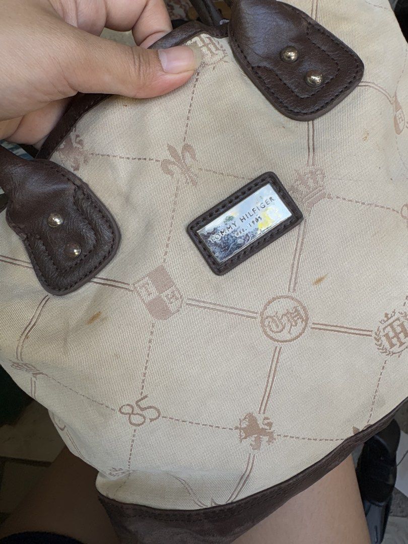 Tommy Hilfiger Monogram hand Bag Brown Cream (Category: Tote Bags) located in Manila. Submitted by dorilorenr48954 (Listing ID 1471227003, Image 2). Description: - Brand: Tommy Hilfiger - Style: Monogram Tote (Cream canvas with brown faux leather trim) - Features: Dual top handles, silver logo plaque on the front - Interior: Blue fabric lining with a signature red Tommy Hilfiger brand patch - Condition: Pre-owned with light stains on the exterior