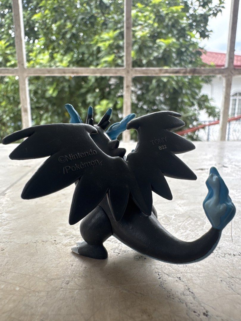 TOMY Pokémon Mega Charizard X Figure Nintendo (Category: Figurines & Statues) located in Quezon City. Submitted by JDC_Onlineshop (Listing ID 1471144681, Image 3). Description: - Authentic TOMY Mega Charizard X collectible figurine - Official Nintendo and Pokémon stamps on the back of the wing - Features the classic black and blue design with red eyes and blue flame tail - Stands on its own securely - Great addition to your Pokémon collection.