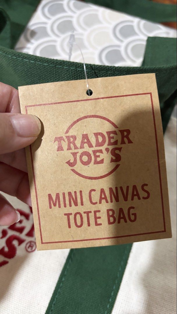 Trader Joe's Mini Canvas Tote Bag Green (Category: Tote Bags) located in Quezon City. Submitted by bella_ciao (Listing ID 1471230335, Image 2). Description: - Brand: Trader Joe's - Item: Mini canvas tote bag - Color: Off-white and green - Condition: Brand new with original paper retail tag attached - Material: Heavy-duty canvas fabric with reinforced straps and bottom panel - Features: Classic red Trader Joe's logo on the front pocket.