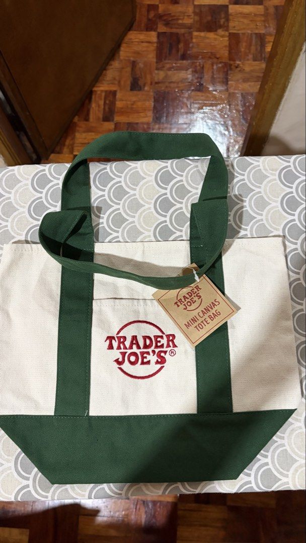 Trader Joe's Mini Canvas Tote Bag Green (Category: Tote Bags) located in Quezon City. Submitted by bella_ciao (Listing ID 1471230335, Image 1). Description: - Brand: Trader Joe's - Item: Mini canvas tote bag - Color: Off-white and green - Condition: Brand new with original paper retail tag attached - Material: Heavy-duty canvas fabric with reinforced straps and bottom panel - Features: Classic red Trader Joe's logo on the front pocket.