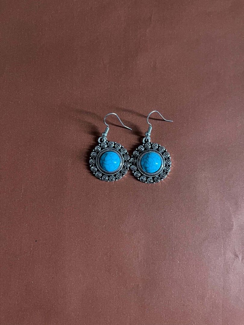 Turquoise and Silver Drop Earrings (Category: Earrings) located in Kananga. Submitted by aurylien.clo (Listing ID 1471130193, Image 1). Description: - Style: Boho drop earrings with vibrant turquoise center stones - Design: Ornate silver-tone metal frames with intricate scrollwork and spiral details - Comfort: Lightweight for all-day wear with standard fishhook wires for pierced ears - Versatility: Perfect eye-catching accessory for daily wear or