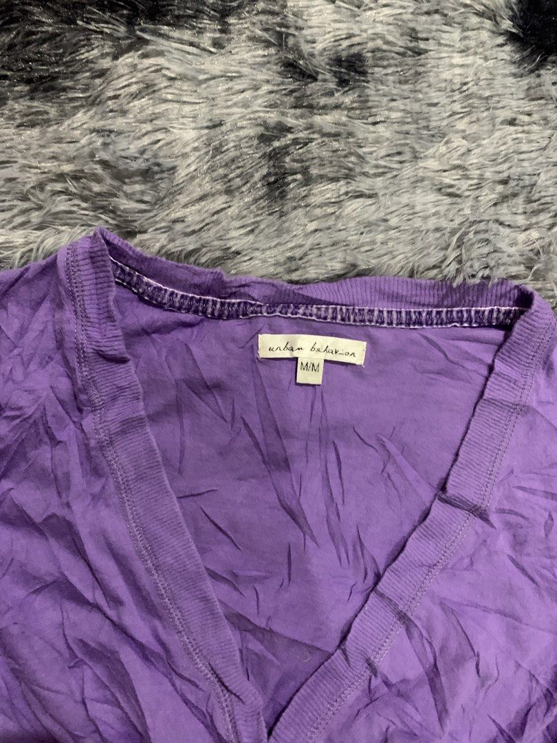 Urban Behavior Purple V-Neck Blouse Size M (Category: Blouses) located in Iba. Submitted by thriftcoyan (Listing ID 1471224185, Image 2). Description: - Brand: Urban Behavior Baby Doll top - Size: Medium - Color: Purple - Neckline: Deep v-neck with ribbed trim - Style: Empire waist with adjustable side ties, short cap sleeves - Material: Lightweight crinkled fabric - Condition/Use: Great casual basic piece for everyday outfits.