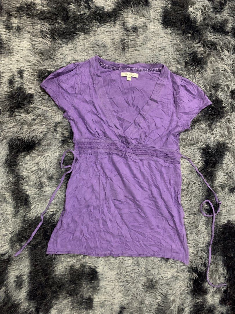 Urban Behavior Purple V-Neck Blouse Size M (Category: Blouses) located in Iba. Submitted by thriftcoyan (Listing ID 1471224185, Image 1). Description: - Brand: Urban Behavior Baby Doll top - Size: Medium - Color: Purple - Neckline: Deep v-neck with ribbed trim - Style: Empire waist with adjustable side ties, short cap sleeves - Material: Lightweight crinkled fabric - Condition/Use: Great casual basic piece for everyday outfits.