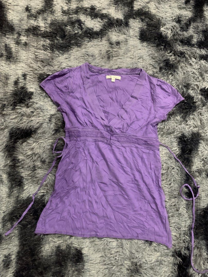 Urban Behavior Purple V-Neck Blouse Size M (Category: Blouses) located in Iba. Submitted by thriftcoyan (Listing ID 1471224185, Image 3). Description: - Brand: Urban Behavior Baby Doll top - Size: Medium - Color: Purple - Neckline: Deep v-neck with ribbed trim - Style: Empire waist with adjustable side ties, short cap sleeves - Material: Lightweight crinkled fabric - Condition/Use: Great casual basic piece for everyday outfits.