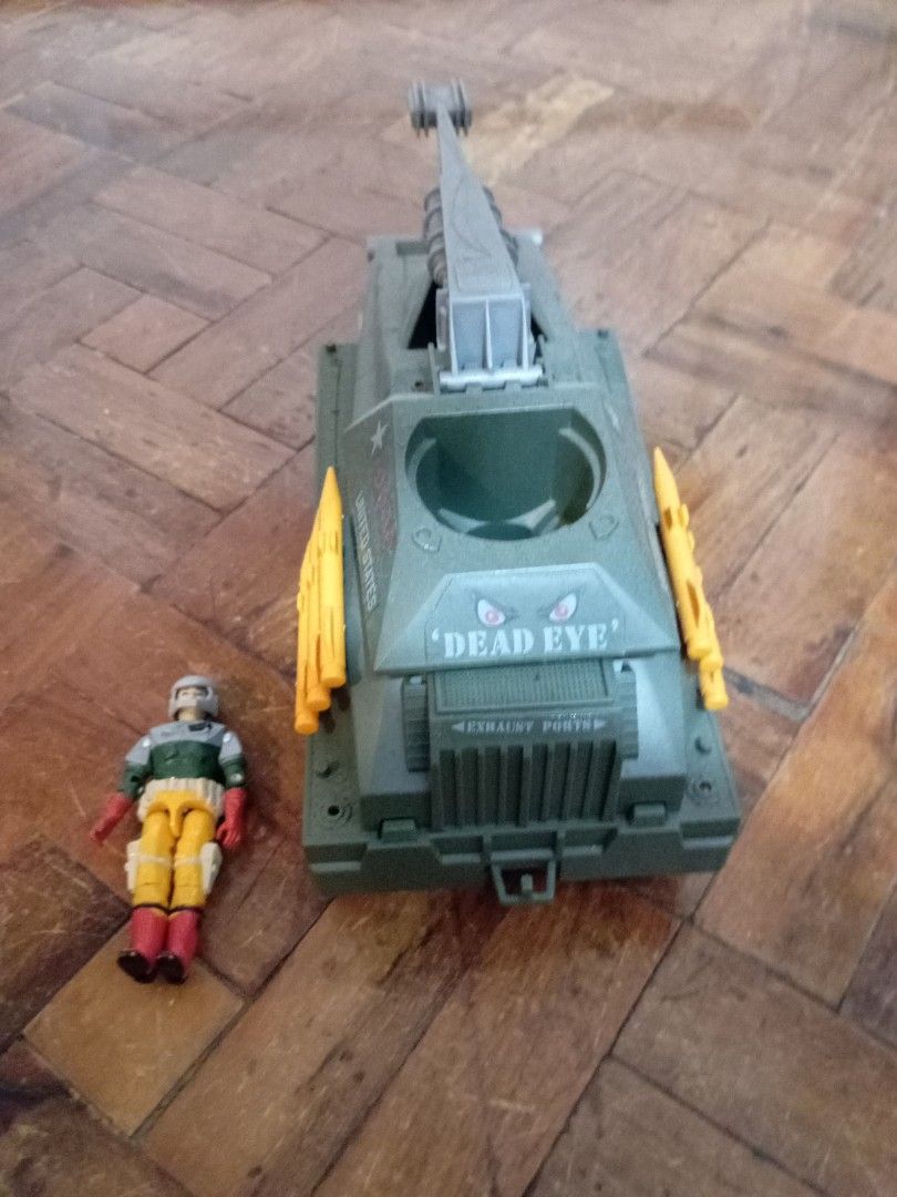 Vintage GI Joe Persuader (Category: Vehicle & Diecast Models) located in Manila. Submitted by johnhunte48138 (Listing ID 1471164326, Image 2). Description: - GI Joe military toy tank with a military green body and rolling black wheels - Features striking orange missiles on the side and a functional gray crane arm on top - "Dead Eye" printed near the front exhaust ports - Includes a matching action figure wearing a helmet, green shirt, and yellow 