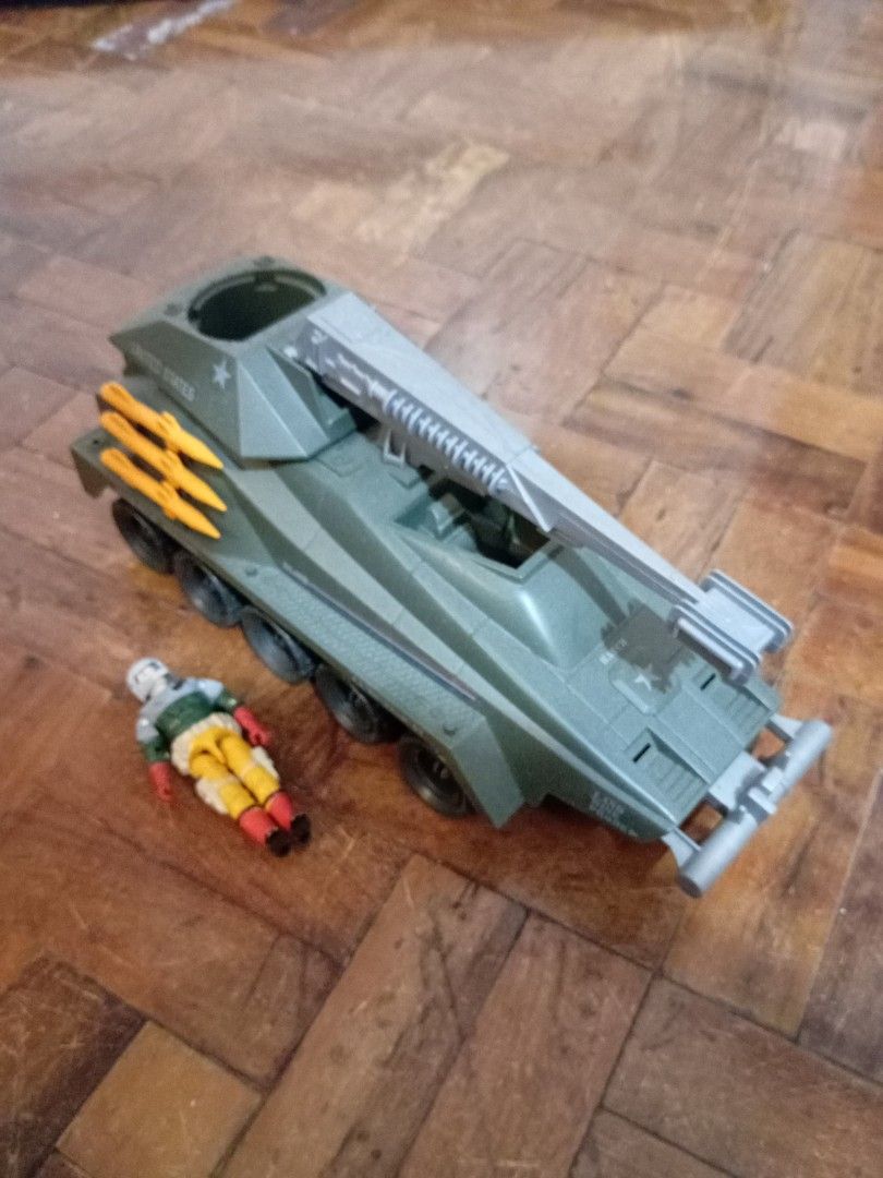Vintage GI Joe Persuader (Category: Vehicle & Diecast Models) located in Manila. Submitted by johnhunte48138 (Listing ID 1471164326, Image 3). Description: - GI Joe military toy tank with a military green body and rolling black wheels - Features striking orange missiles on the side and a functional gray crane arm on top - "Dead Eye" printed near the front exhaust ports - Includes a matching action figure wearing a helmet, green shirt, and yellow 