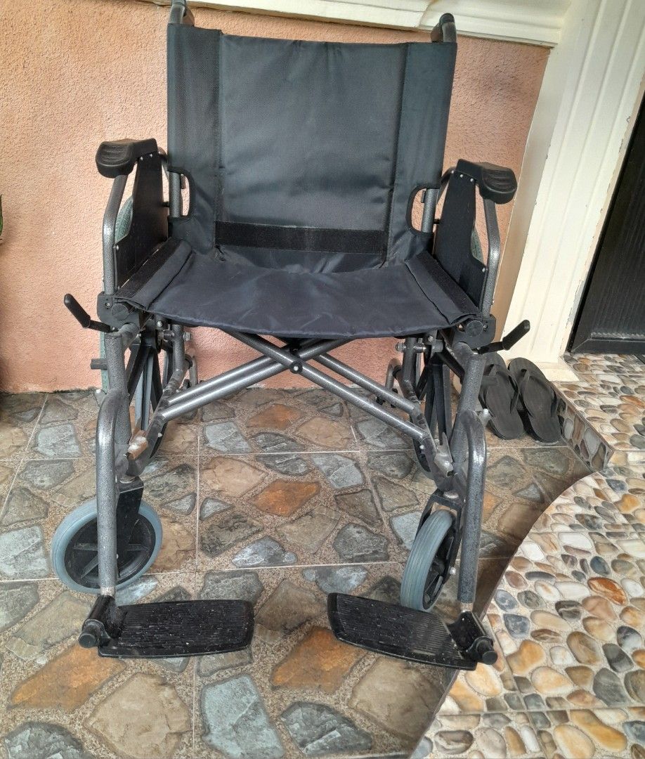 Wheelchair Heavy Duty (Category: Wheelchairs) located in Silang. Submitted by trish125 (Listing ID 1471197888, Image 2). Description: - Condition: Clean and 100% working smoothly - Frame: Sturdy grey metal with black fabric seat - Mobility: Large rear wheels with hand rims and small front casters - Features: Includes footrests - Portability: Folds up easily for car trunk storage - Fulfillment: Ready for pickup.
