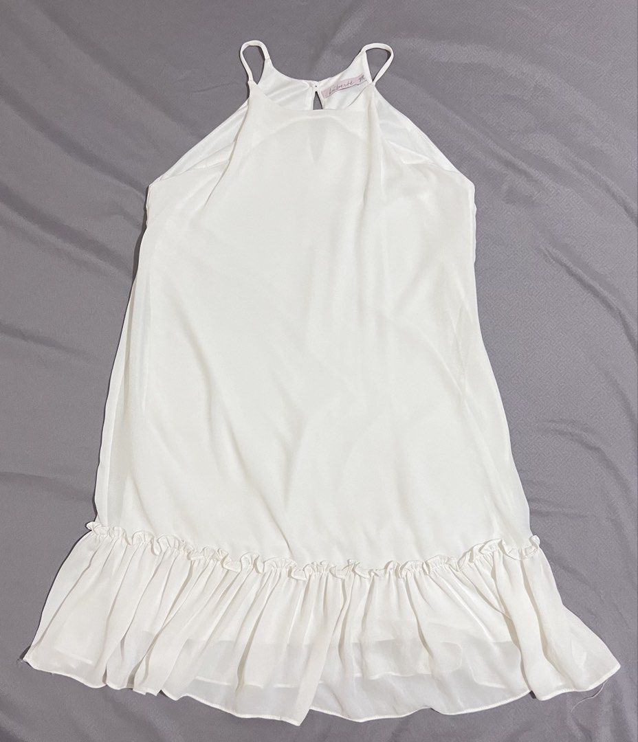 White Halter Neck Ruffle Hem Dress (Category: Dresses) located in Cainta. Submitted by periwinkle.ph (Listing ID 1471171984, Image 1). Description: - Brand: Liberté - Style: Sleeveless white dress with halter neckline and spaghetti straps - Details: Back button closure with a chic keyhole cutout and playful ruffle hem - Fabric: Lightweight and breathable chiffon-like material - Condition: Excellent, perfect for sunny days and casual outings.