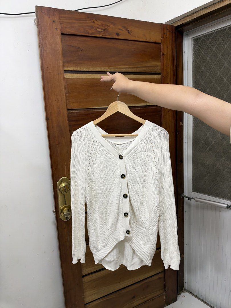 White Knitted V-Neck Cardigan (Category: Coats, Jackets and Outerwear) located in Cavite. Submitted by yakultjeni85475 (Listing ID 1471285200, Image 3). Description: - Color: White - Style: Oversized cardigan with V-neckline and dark front buttons - Material & Texture: Chunky knit fabric with ribbed cuffs and hem - Design: Modern high-low hemline - Fit: Comfortable and versatile - Best for: Layering over basic tops or turtlenecks during cooler we