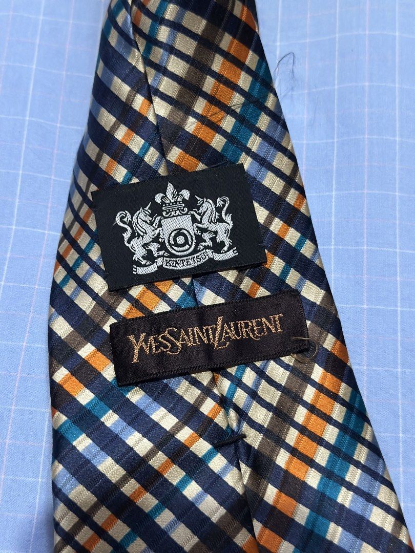 Yves Saint Laurent Plaid Silk Tie (Category: Ties) located in Daet. Submitted by thrifthings2018 (Listing ID 1471195478, Image 2). Description: - Brand: Yves Saint Laurent (YSL) - Material: 100% High-quality Silk - Design: Vibrant plaid check in navy blue, orange, teal, and cream - Details: Signature YSL branded lining on the back, classic pointed blade shape - Condition: Excellent pre-owned condition - Styling: Ideal for formal wear, business me