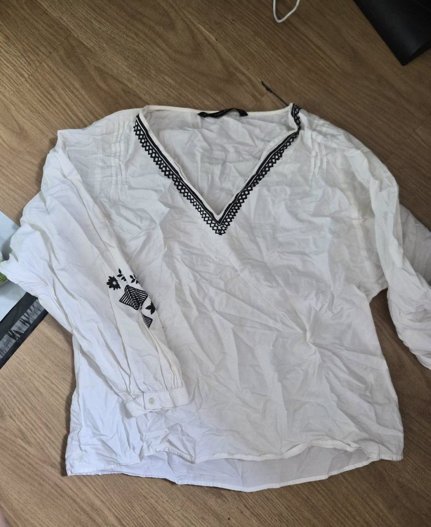 Zara Embroidered V-Neck White Blouse (Category: Blouses) located in Cavite. Submitted by frombellas (Listing ID 1471201780, Image 3). Description: 📍 Sadly, due to storage there's small patches seen on the top. - Brand: Zara - Color: White with black geometric embroidery - Material: Lightweight cotton, relaxed fit - Design: V-neck and dramatic bishop sleeves with button cuffs - Style: Casual wardrobe staple, perfect with jeans or trousers.