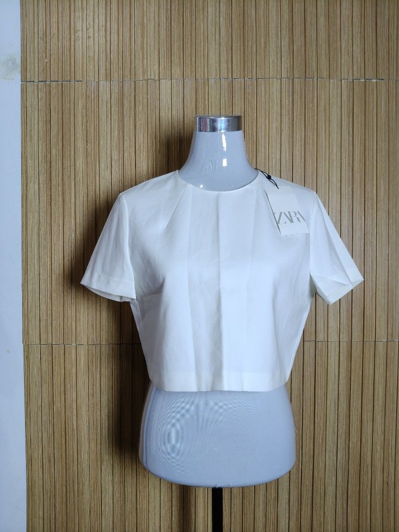 Zara White Short Sleeve Crop Top (Category: Blouses) located in Taguig. Submitted by ashie_clothing (Listing ID 1471256780, Image 1). Description: - Brand: Zara - Style: Crop top with short sleeves and round neckline - Size: XL - Condition: Brand new with original store tags attached - Details: Clean solid white color, concealed back zip closure - Fit: Great basic piece, perfect for pairing with high-waisted bottoms.