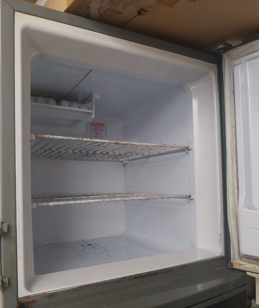Condura Two-Door Refrigerator (Category: Refrigerators and Freezers) located in Pasig City. Submitted by rare.ashima25 (Listing ID 1471338085, Image 3). Description: Condura two-door fridge in dark gray finish. Top freezer compartment includes wire shelving and door pocket. Main lower section has standard shelving space. Exterior shows smudges and wear marks. Rubber seals around doors show visible dirt accumulation and staining. Clean-up needed b