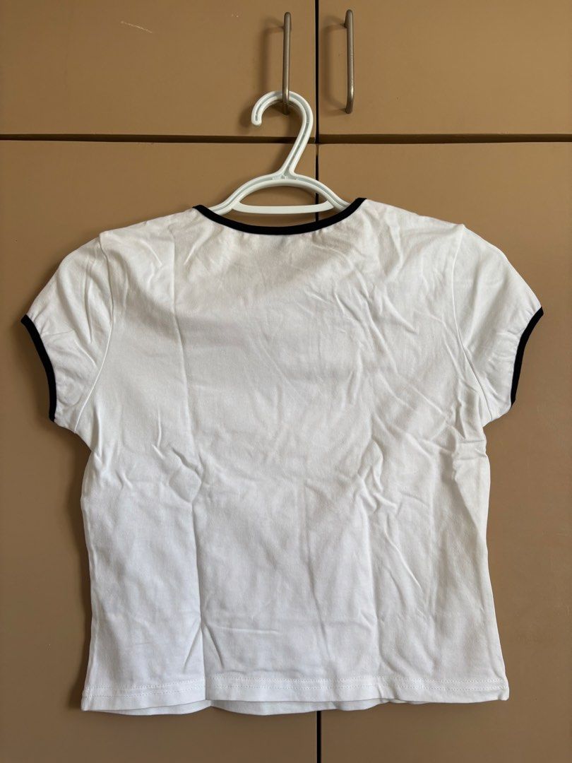 Dazy White Tee with Black Star (Category: Shirts) located in Davao. Submitted by lazicloud (Listing ID 1471343300, Image 2). Description: - Brand: Dazy - Size: Medium (M) - Design: White ringer tee with contrast black ribbed trim on collar and sleeves - Graphic: Large black star printed on the center chest - Fit: Cropped fit, short sleeves - Material: Soft and comfortable cotton blend - Styling: Versatile piece, easy to match with denim or skirts