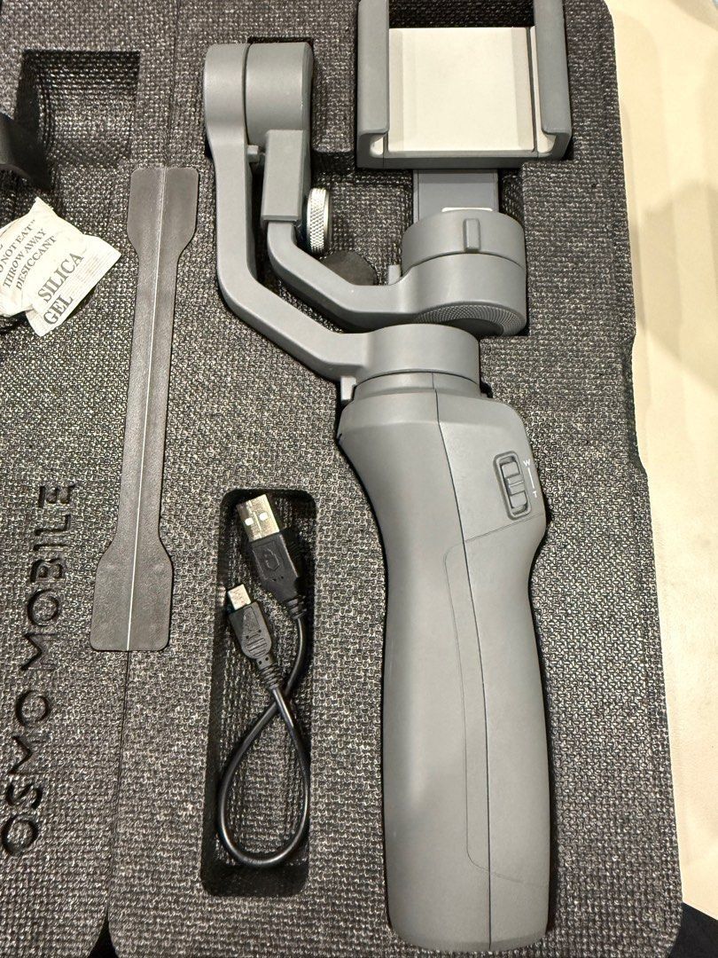 DJI Osmo Mobile 2 Smartphone Gimbal Stabilizer - Negotiable!!! (Category: Gimbals & Stabilizers ) located in Manila. Submitted by axelyuna.27 (Listing ID 1471332023, Image 3). Description: - Brand: DJI Osmo Mobile 2 Smartphone Gimbal Stabilizer - Condition: Excellent, clean grey finish - Included: Protective molded foam case with organized slots - Accessories: Charging cable, mini tripod stand, and accessory mount included - Features: Smooth stab