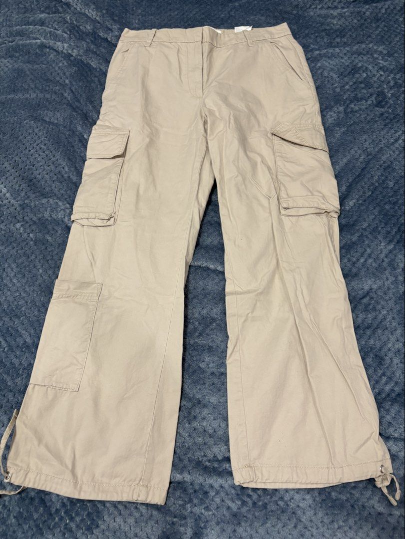 H&M Beige Cotton Cargo Pants (Category: Other Bottoms) located in Marilao. Submitted by luckystone_0cdaee (Listing ID 1471298076, Image 1). Description: H&M beige cotton cargo pants feature a classic utility design with signature oversized flap side pockets, a flat front waistband with hidden closures, and adjustable toggle drawstrings at the bottom cuffs for a customizable straight-leg or cinched look. Size: can fit 30-32 waist Length: 38".