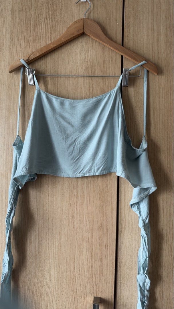 Light blue spaghetti strap crop top with side ties (Category: Sleeveless) located in Mandaluyong City. Submitted by andreyamari_ (Listing ID 1471354934, Image 2). Description: - Color: Light Blue - Style: Summer crop top with square neckline and thin shoulder straps - Feature: Trendy long side ties hanging from the hem - Material: Lightweight and breathable fabric - Pairing: Perfect to match with high-waist jeans or shorts.