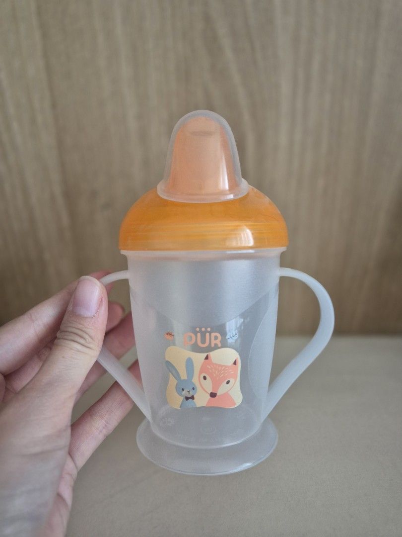 PUR baby training sippy cup with handles (Category: Weaning & Toddler Feeding) located in San Juan City. Submitted by apetitegirl (Listing ID 1471412274, Image 1). Description: - Brand: PUR - Color: Translucent white and orange with cute fox and bunny graphics - Double handle design for easy independent holding by little hands - Spout lid with protective cover to keep the mouthpiece clean - Easy to take apart for thorough, hassle-free cleaning - 