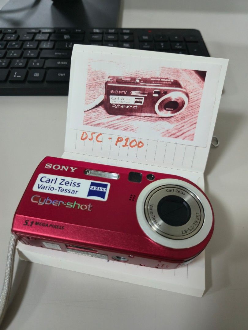 Sony Cyber-shot DSC-P100 Red Digital Camera (Category: Cameras) located in Malvar. Submitted by jobellicious (Listing ID 1471310539, Image 1). Description: JAPAN PASABUY ETA DEC 18TH 100% Working - Model: Sony Cyber-shot DSC-P100 - Color: Striking Red - Resolution: 5.1 Megapixels - Optics: Carl Zeiss Vario-Tessar lens - Condition: Powers up fine, compact retro point-and-shoot body - Inclusions: Hand strap attached - Storage: Uses standard memory 