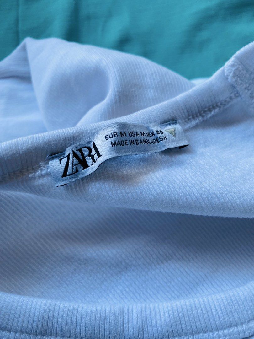 Zara White Ribbed T-Shirt Medium (Category: Shirts) located in Caloocan City. Submitted by lovemyclothes21 (Listing ID 1471340384, Image 2). Description: - Brand: Zara - Color: White - Size: Medium - Neckline: V-neck with short sleeves - Fit: Fitted silhouette - Material: Comfortable cotton blend - Origin: Made in Bangladesh - Condition: Excellent / Like new - Style: Basic wardrobe essential that pairs easily with any outfit.