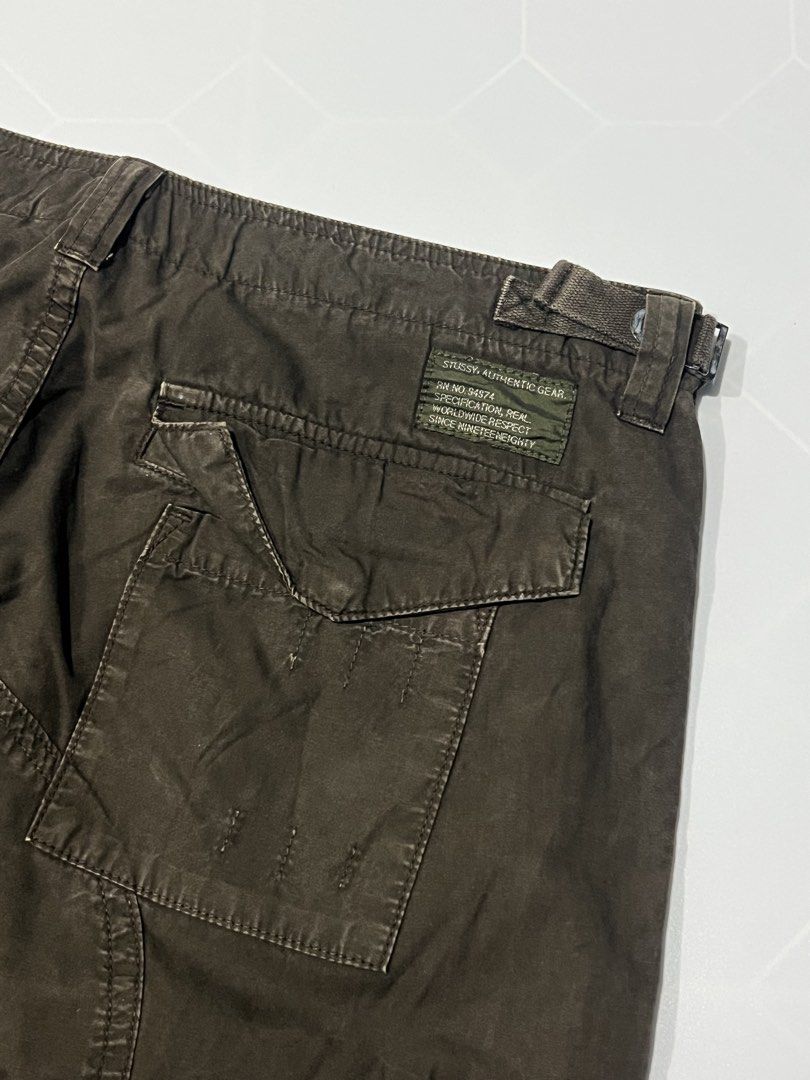 90’s Stussy Authentic Gear Cargo Pants Brown (Category: Jeans) located in Caloocan City. Submitted by lostarchive_55 (Listing ID 1465917630, Image 3). Description: - Brand: Stussy Authentic Gear - Style: Cargo pants with relaxed fit through the leg - Color: Dark brown wash - Size: 32 (adjustable waist tabs on both sides for a custom fit) - Pockets: Utility thigh pockets with button closures, extra right-leg zip pocket, and rear flap pockets - Det