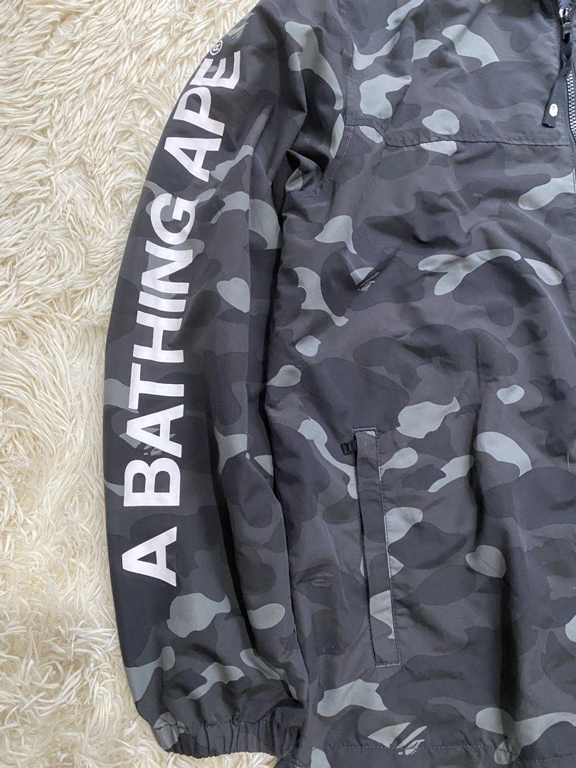 A Bathing Ape BAPE Camo Windbreaker Jacket Size L (Category: Coats, Jackets and Outerwear) located in Manila. Submitted by switchcity (Listing ID 1465898677, Image 2). Description: - Brand: BAPE (A Bathing Ape) - Item: Dark Grey Camo Windbreaker - Size: L (Tag inside collar) - Design: Large A BATHING APE text printed down the right sleeve - Features: Full zip closure, dual front pockets, drawstring hood, elastic cuffs - Materials: 100% nylon shel
