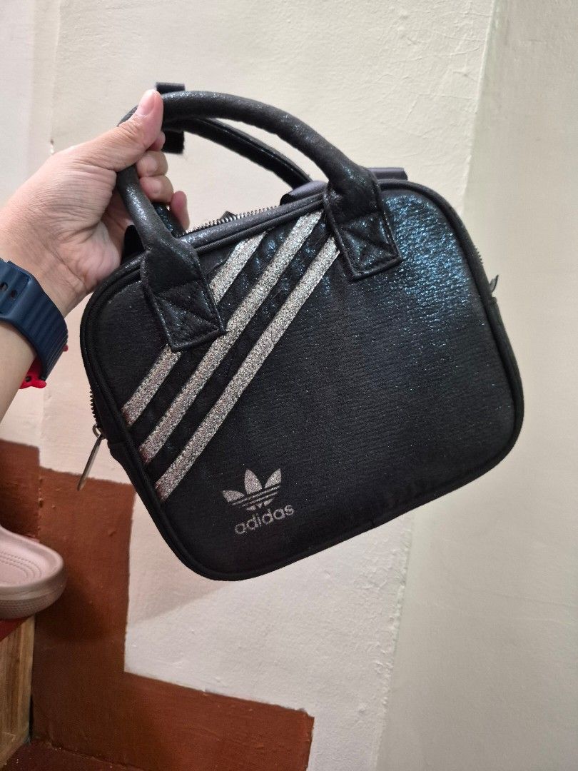 Adidas Black Glitter Mini Handbag (Category: Luxury Bags & Wallets) located in Antipolo. Submitted by prinsesa_dianne (Listing ID 1465940362, Image 1). Description: - Brand: Adidas - Style: Mini handbag / everyday casual bag - Color/Design: Black glitter with silver three stripes on the front - Closure & Handles: Secure zipper closure with dual carry handles - Interior: Clean fabric lining featuring the classic Adidas brand logo label patch - Con