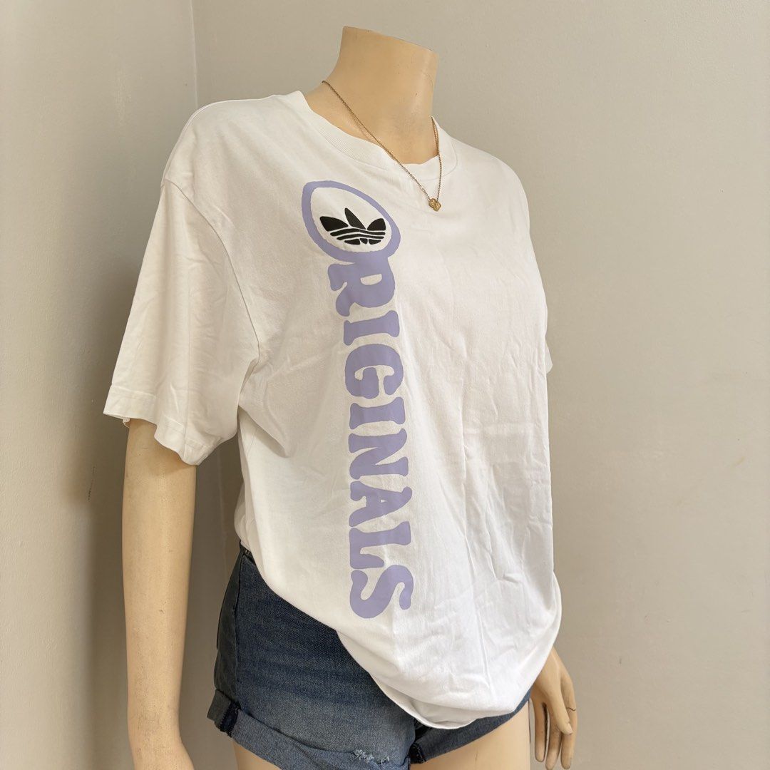 Adidas White Graphic Shirt with backprint (Category: Shirts) located in Imus. Submitted by reloved.nd (Listing ID 1465814232, Image 2). Description: - Brand: Adidas Originals - Color: White with light purple front text and black back graphic - Size: Medium (M) - Style: Short sleeves, crew neck - Design: Front trefoil logo and 'Originals' text; back features 'Always have been, always will beeeee' print with infinity symbols and running figures - C