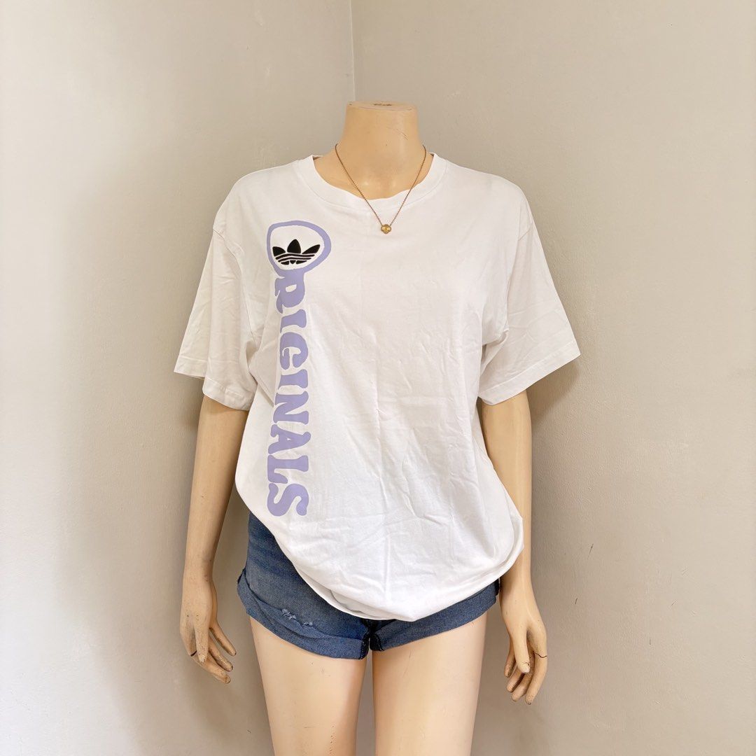 Adidas White Graphic Shirt with backprint (Category: Shirts) located in Imus. Submitted by reloved.nd (Listing ID 1465814232, Image 1). Description: - Brand: Adidas Originals - Color: White with light purple front text and black back graphic - Size: Medium (M) - Style: Short sleeves, crew neck - Design: Front trefoil logo and 'Originals' text; back features 'Always have been, always will beeeee' print with infinity symbols and running figures - C