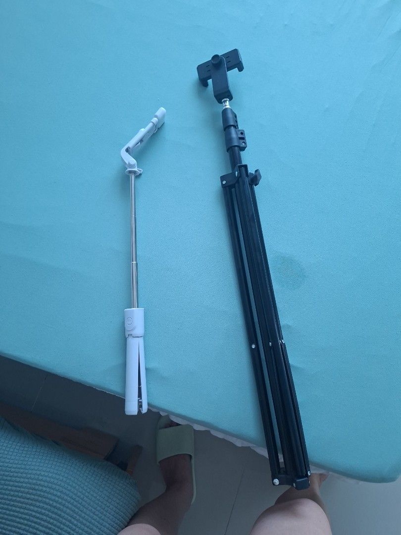 Adjustable phone tripod and selfie stick stand (Category: Tripods & Monopods) located in Mandaluyong City. Submitted by vhiedns (Listing ID 1465894586, Image 2). Description: - Includes 2 portable phone holders for travel and content creation - Black folding tripod stand features extendable legs and an adjustable phone clamp - White compact selfie stick comes with an extendable metal pole and built-in remote button - Both items fold down small to
