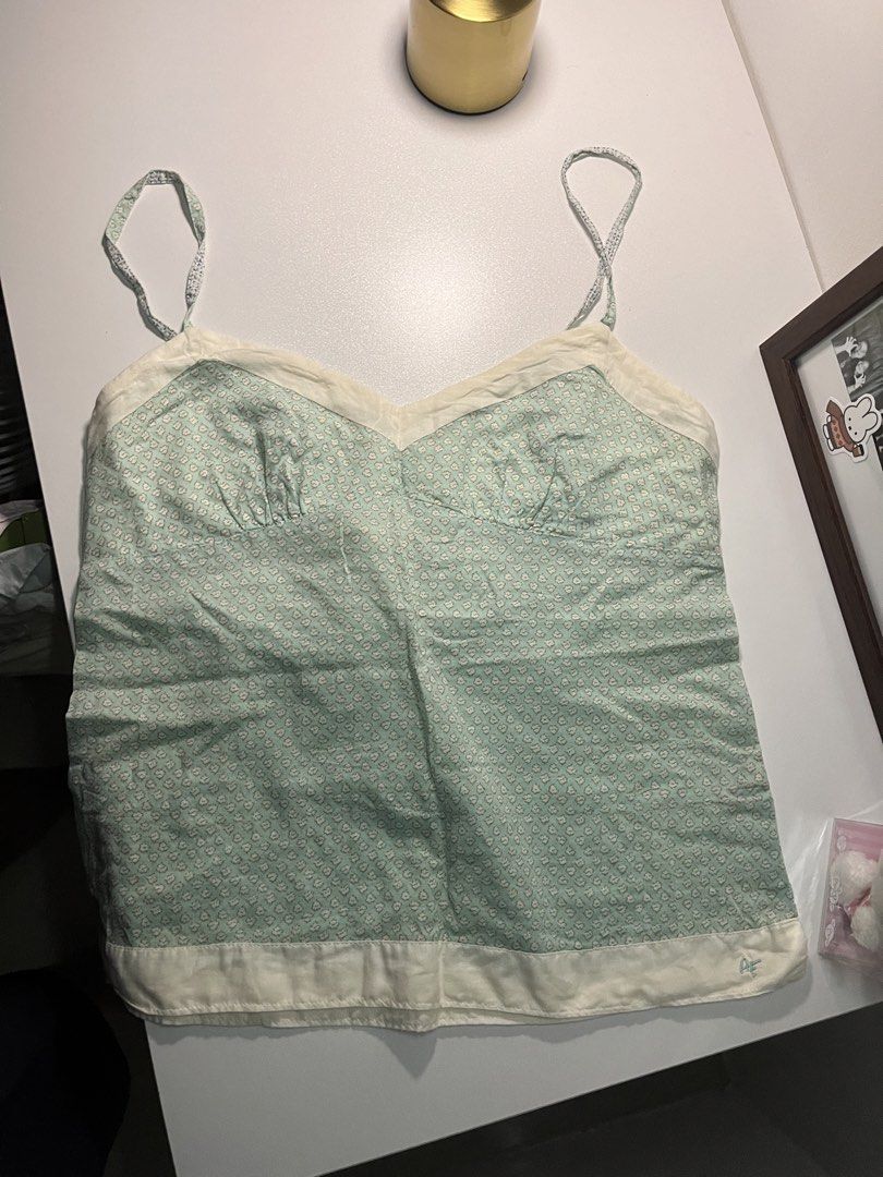 American Eagle Green Floral Print Cami Top (Category: Sleeveless) located in Bacolod City. Submitted by miffywhitematcha (Listing ID 1465912220, Image 3). Description: - Style: Green and white floral print camisole - Details: Sweetheart neckline, white contrast trim, and a small blue embroidered logo near the hem - Straps: Thin spaghetti straps - Material: Lightweight and breathable fabric - Fit & Pairing: Great for warm weather, easy to style wi