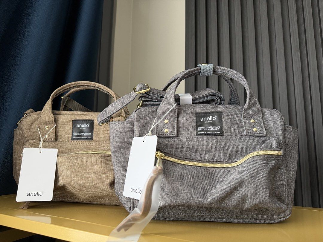Anello Shoulder Bag Grey Canvas Handbag (Category: Cross-body Bags) located in Manila. Submitted by purestar.01 (Listing ID 1465762841, Image 1). Description: - Brand: anello - Color: Grey canvas with textured fabric finish and black brand label - Hardware: Gold accents with zippered front pocket - Features: Dual top handles, long strap, and multiple interior compartments - Condition: Brand new with tags attached, zipper pull still wrapped in pla