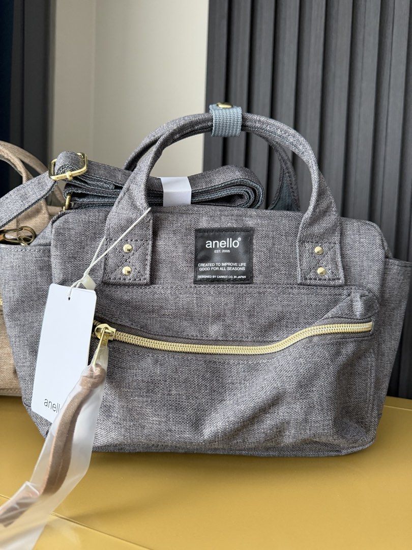 Anello Shoulder Bag Grey Canvas Handbag (Category: Cross-body Bags) located in Manila. Submitted by purestar.01 (Listing ID 1465762841, Image 2). Description: - Brand: anello - Color: Grey canvas with textured fabric finish and black brand label - Hardware: Gold accents with zippered front pocket - Features: Dual top handles, long strap, and multiple interior compartments - Condition: Brand new with tags attached, zipper pull still wrapped in pla