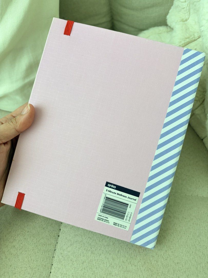 Anko Wellness Journal (Category: Stationery & School Supplies) located in Makati City. Submitted by makatigirlpreloved (Listing ID 1465828511, Image 2). Description: - Brand: Anko - Item: 5-Minute Wellness Journal - Color/Design: Pink cover with blue and white striped spine, secured with a red elastic band - Condition: Brand new, clean, and completely unwritten pages - Features: Daily prompts for gratitude, affirmations, daily highlights, and ref