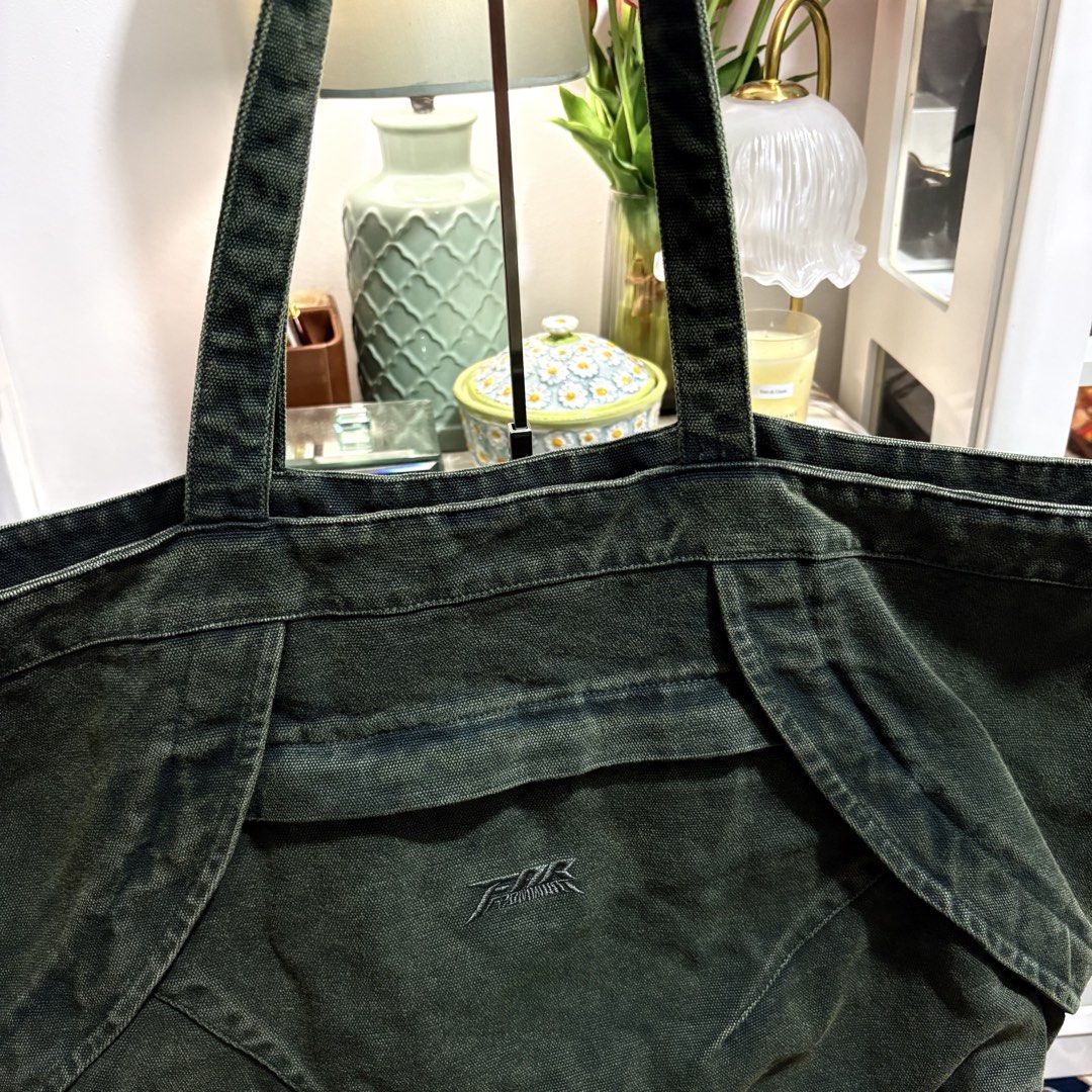 Authentic FAR BIG TOTE BAG_BLUE GREEN (Category: Tote Bags) located in Binangonan. Submitted by makoleksyon (Listing ID 1465897944, Image 2). Description: Material: Made from 100% thick, double-layered cotton denim fabric, giving it a heavy and structured feel. Design Features: It has a distinctive wide, curved panels design on the front with a stylized, embroidered central logo reading "FAR". It also includes a large main storage compartment and