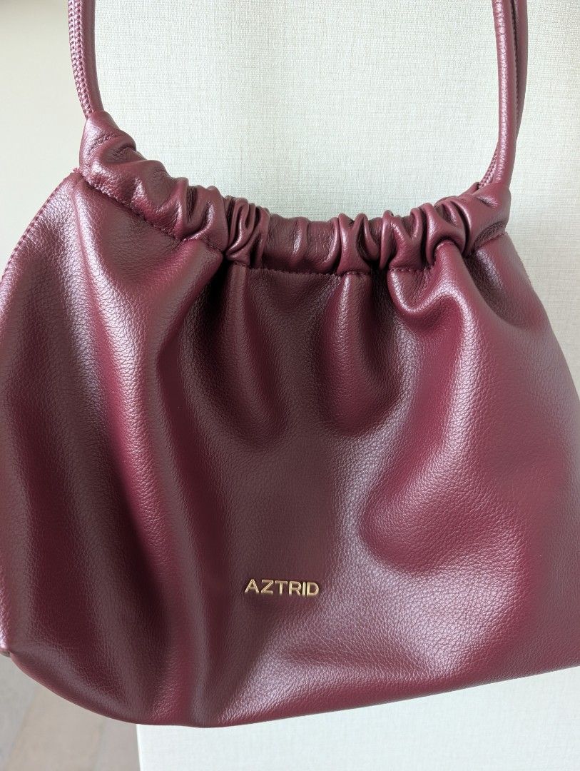 AZTRID Medium Dumpling Bag (Category: Shoulder Bags) located in Makati City. Submitted by g.jo.h (Listing ID 1465952932, Image 2). Description: used 2x only - Brand: AZTRID - Color: Rich Maroon - Material: Premium faux leather with gold-tone hardware - Design: Stylish gathered/pleated top opening with front logo lettering - Straps: Comfortable dual slim straps - Interior: Clean fabric lining with a convenient inner zip pocket and branded leather 