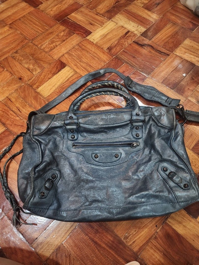 Balenciaga City Bag (Category: Luxury Bags & Wallets) located in Caloocan City. Submitted by jeijei1111 (Listing ID 1465928288, Image 2). Description: - Blueish Gray color - Lampo zip all 3 with $ sign on zipper - Metal plate inside - Bar code at back of plate inside - Edges on front design - small hardware PLEASE NOTE ISSUES: - Worn out ties on handle - No leather tie infront zipper - No mirror - For your own authentication please, NGA.