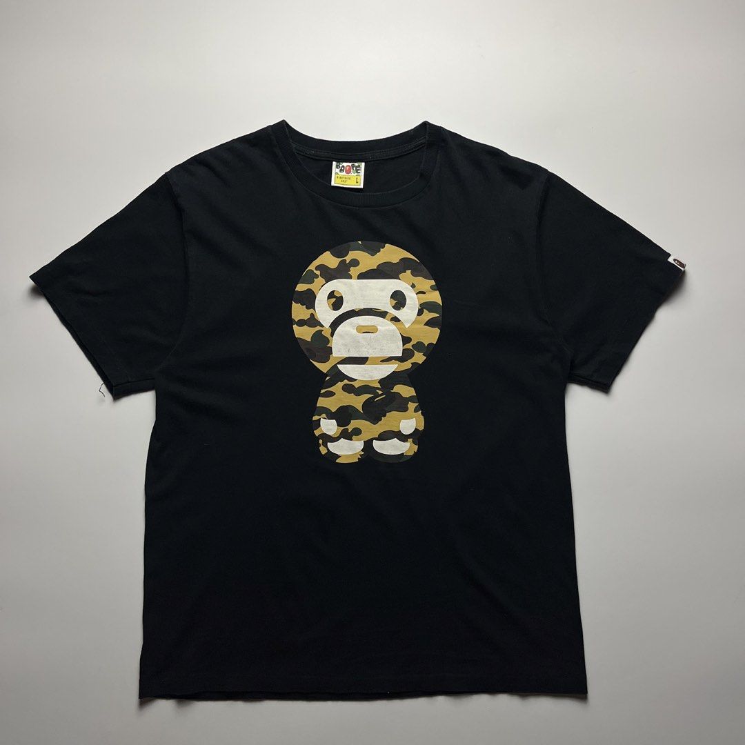 BAPE “Baby Milo” Camouflage Tee (Category: Tshirts & Polo Shirts ) located in Manila. Submitted by streetsavvy (Listing ID 1465863963, Image 1). Description: BAPE “Baby Milo” Camouflage Tee Size: Large Width: 21” Length: 27.5” Shoulder: 18.5” Sleeve Length: 8.5” Hem: 21.5” Measured in Inches Condition: Very good condition with signs of wear Flaw: Hairline cracks Made in China 100% Cotton .