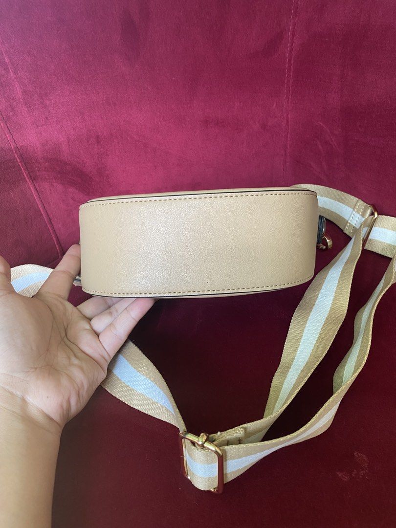 Beige Saddle Crossbody Bag with Striped Strap (Category: Cross-body Bags) located in La Trinidad. Submitted by kinleyky (Listing ID 1465766896, Image 2). Description: - Color: Versatile neutral beige with smooth faux leather finish - Strap: Thick, adjustable white and tan striped pattern - Hardware: Elegant gold-tone accents - Closure: Secure front flap with magnetic snap - Interior: Main compartment, 1 zippered pocket, and 1 open slip pocket - S