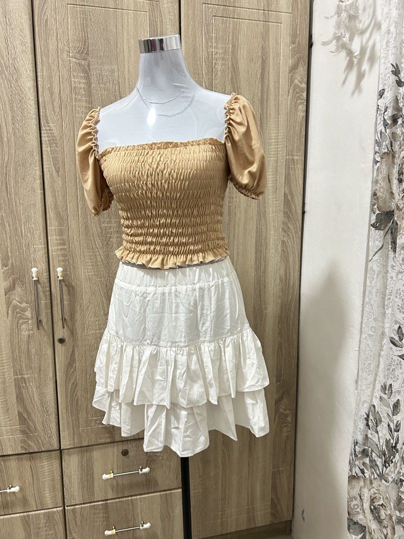 Beige smocked crop top (Category: Others Tops) located in Cavite. Submitted by cl09-39734 (Listing ID 1465821351, Image 1). Description: - Complete matching set: Beige crop top and white tiered ruffle mini skirt - Top details: Smocked elastic bodice and trendy short puff sleeves - Skirt details: Flouncy tiered layers with a comfortable elastic waistband - Versatile style: Ideal for casual outings, dates, or beach vacations - Condition: Brand new 